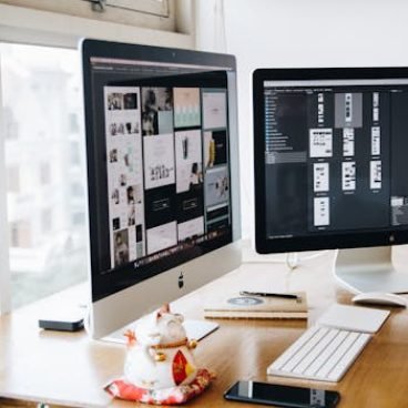 pexels-photo-326502-326502 A sleek modern office setup featuring dual monitors, Apple devices, and creative decor in an indoor workspace.